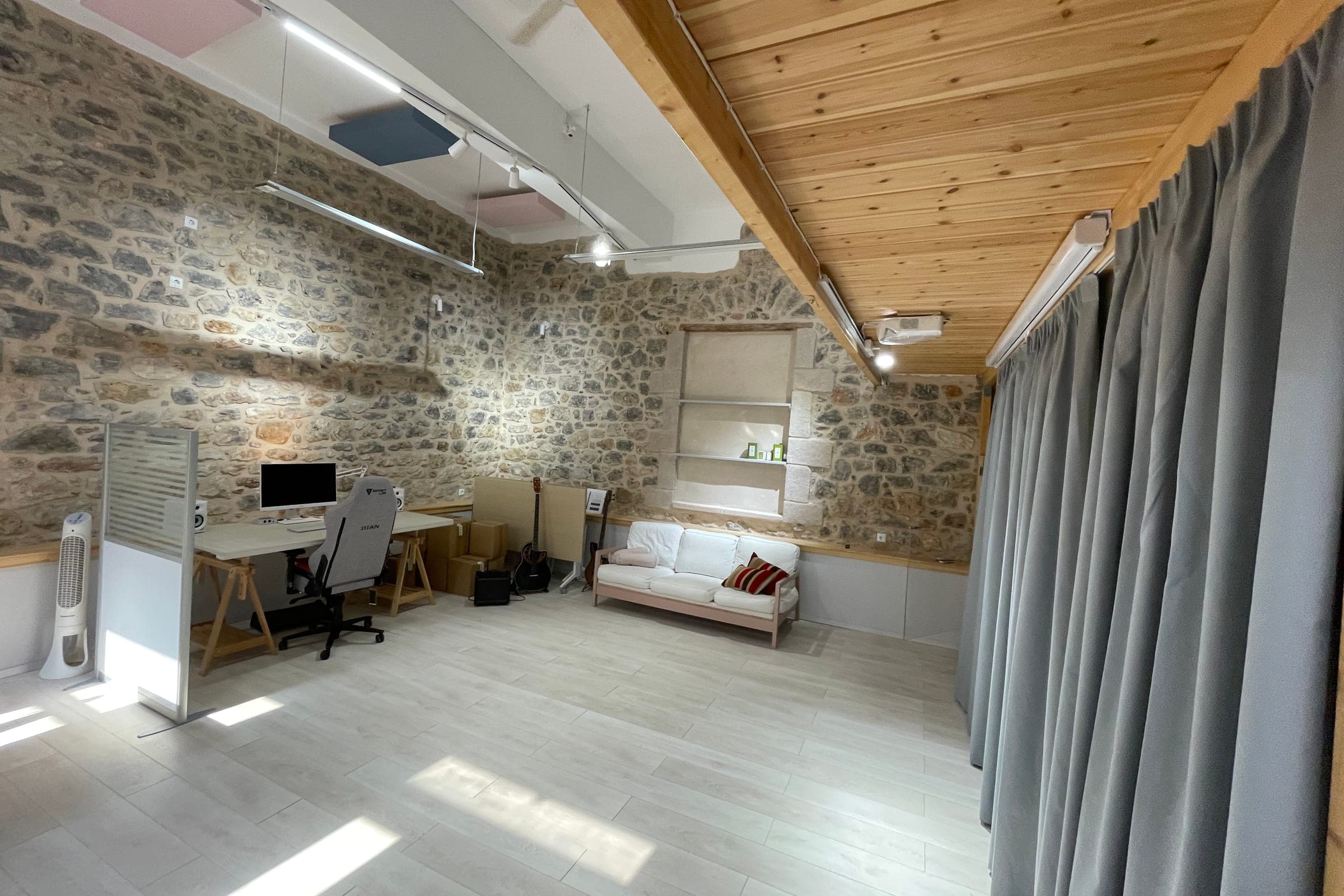 open floor in front of grey curtains, with a ceiling projector and a roll-up screen